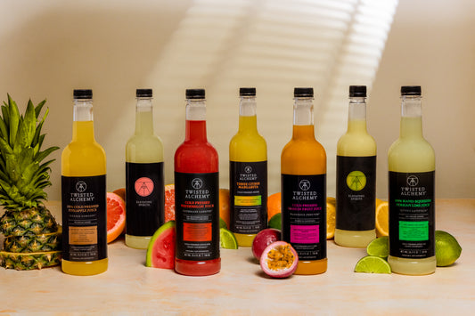 A line of colorful juices surrounded by various fruits against a white background