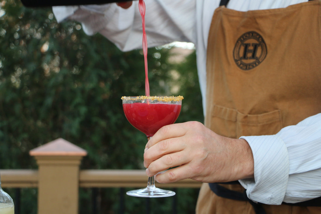 A bright red drink being poured into a coup glass.