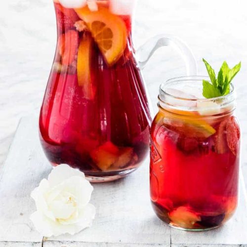Sangria batch in a pitcher to the right of a glass of sangria