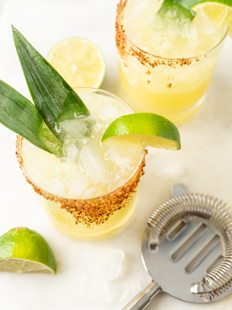 pineapple margarita cocktail shown with fresh agave leaf garnish and lime slice, featuring a Tajin cocktail rim