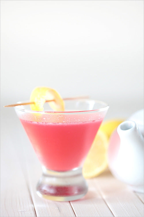 blushing lady cocktail in a triangular glass with lemon twist