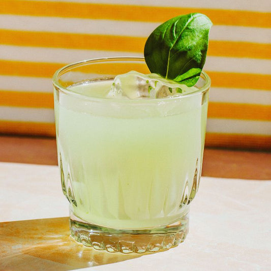 Lime cocktail with mint leaf on yellow and white striped background