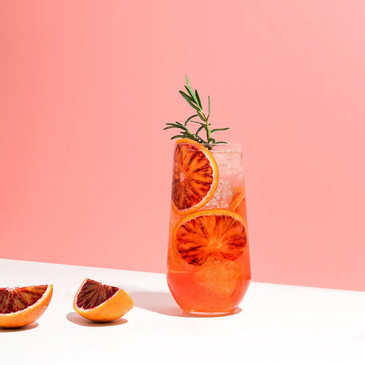 Blood orange cocktail shown on pink background on white table