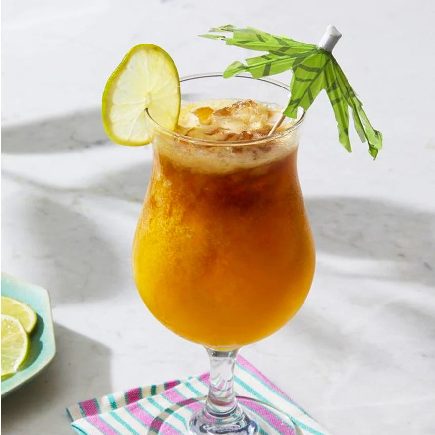 Passion fruit mai thai shown in round glass with a lime slice and tropical umbrella in the drink on a white background