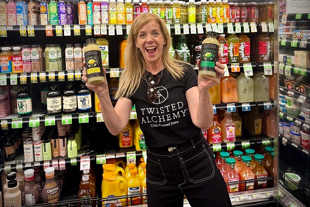 Woman holding two bottles of Twisted Alchemy products in a grocery store aisle.
