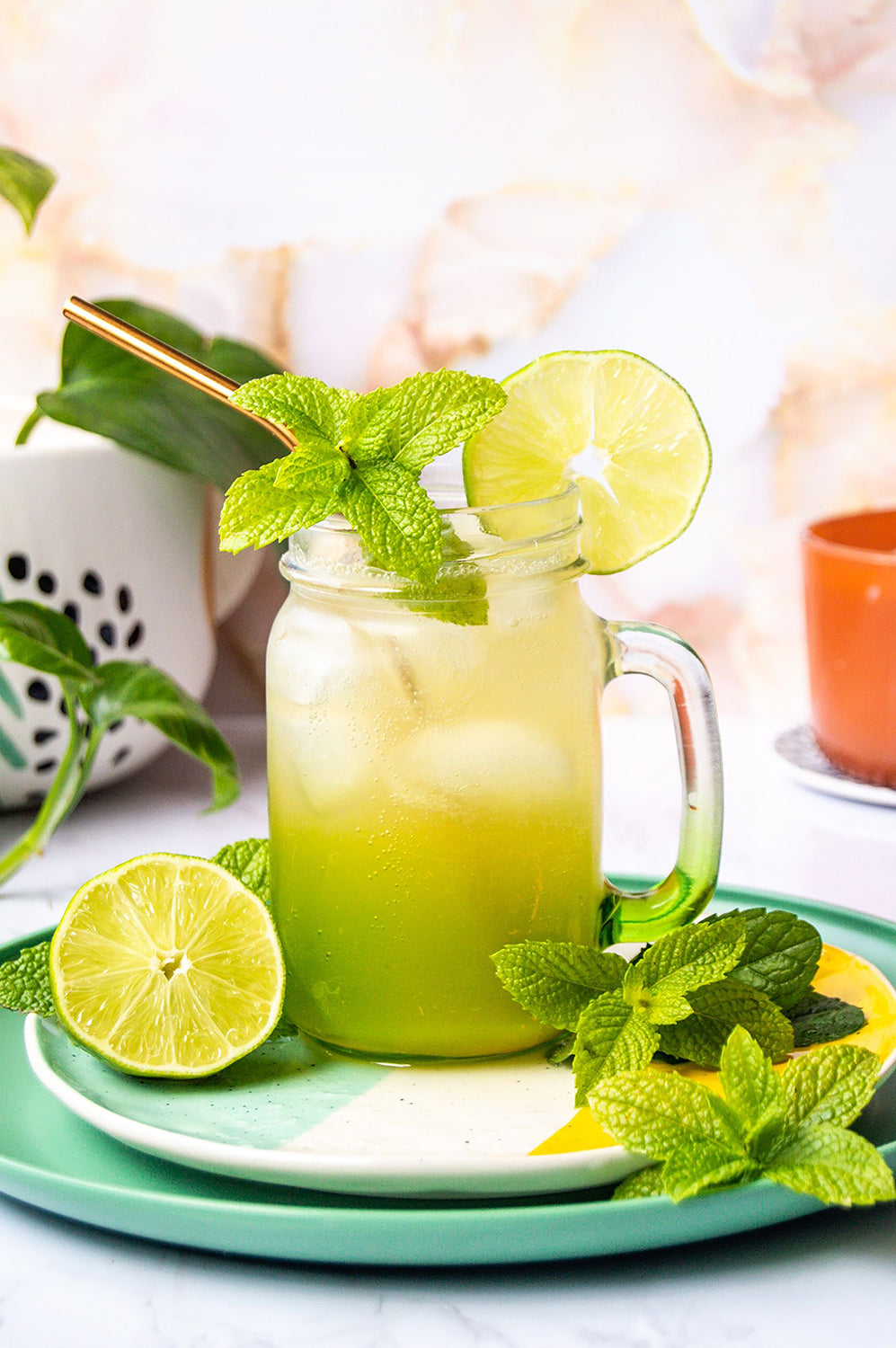 A lime green cocktail with mint garnish and lime slices