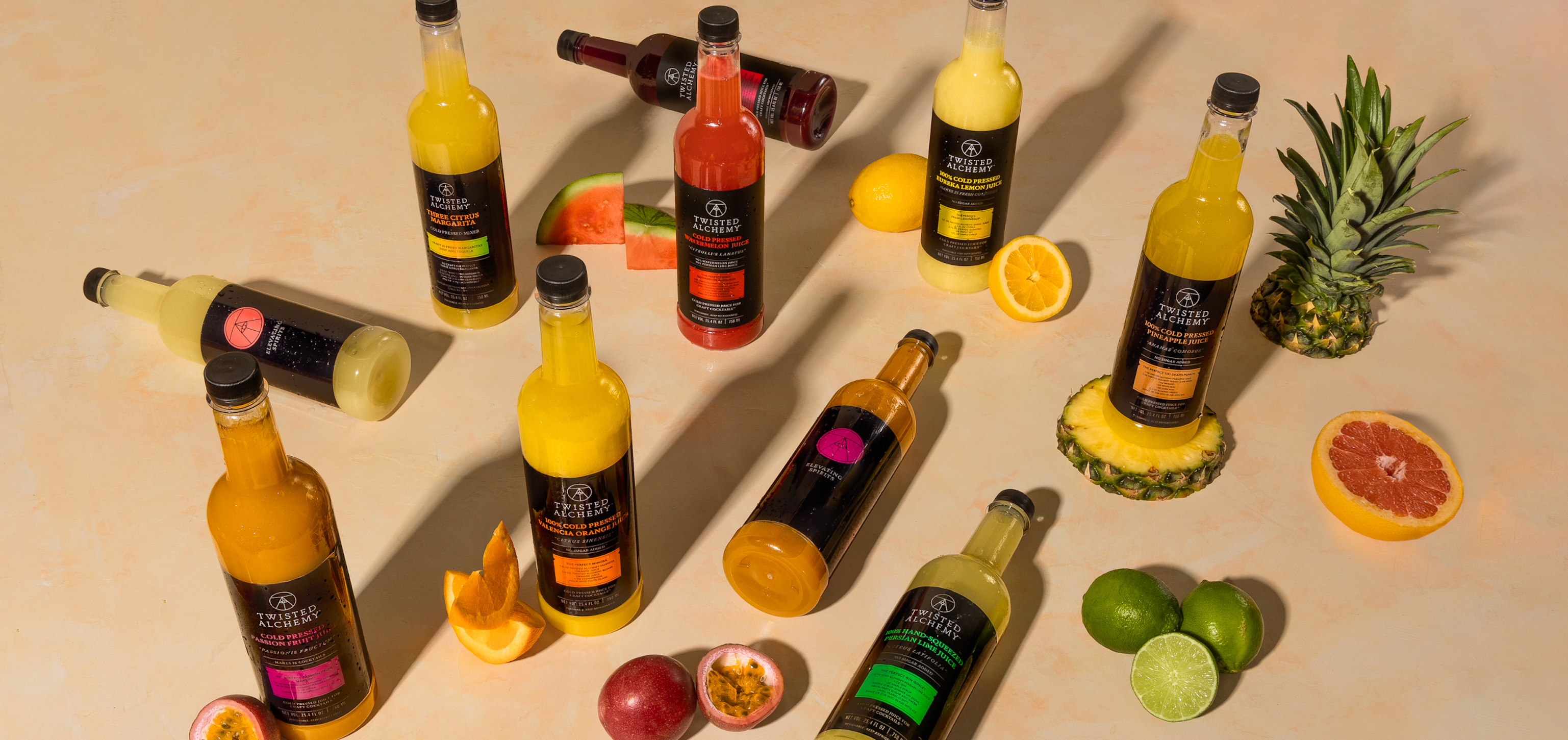Assorted Twisted Alchemy bottles on a table surrounded by cocktails