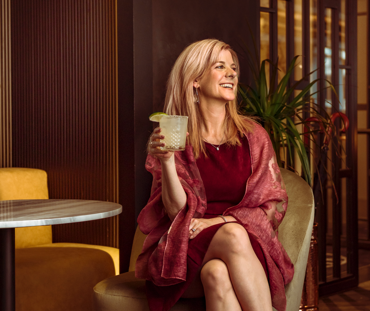 Twisted Alchemy founder Kim Holstein shown with cocktail in hand