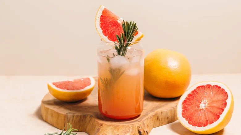 Glass of pink grapefruit juice with a slice of grapefruit on a wooden board.